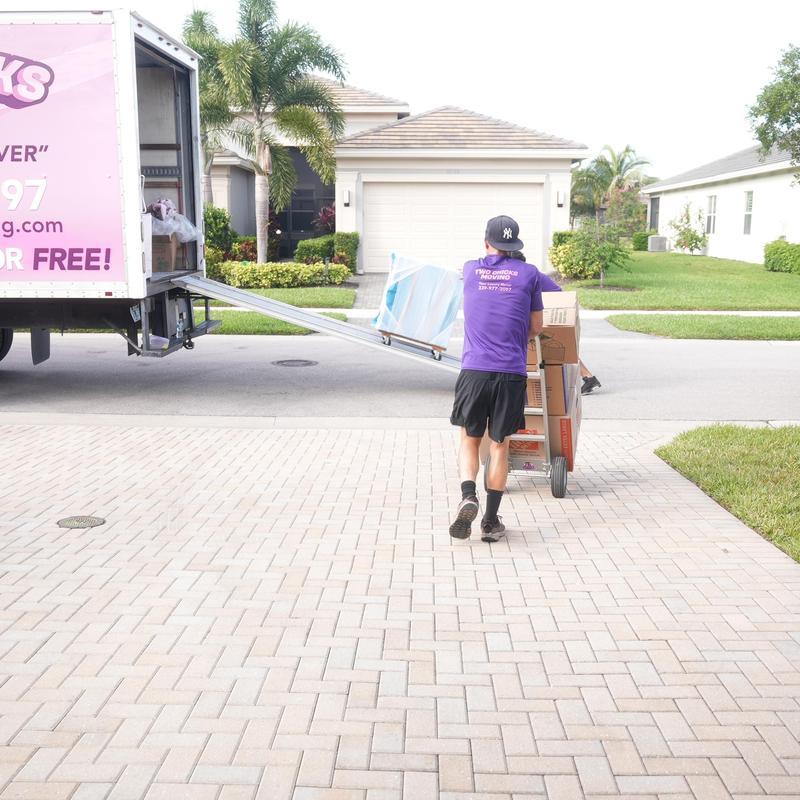 Moving boxes on dolly near moving truck in driveway