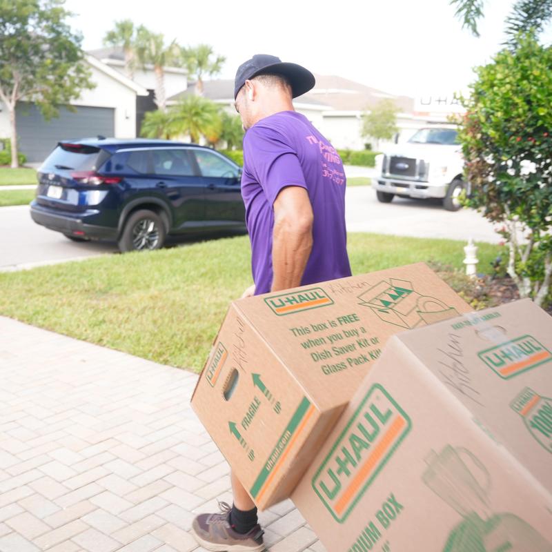 U-Haul moving boxes carried by mover in neighborhood