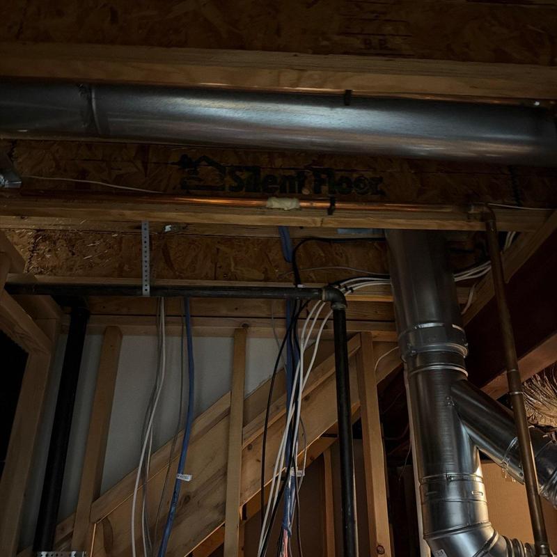 Copper water pipes and metal ductwork installation under stairs