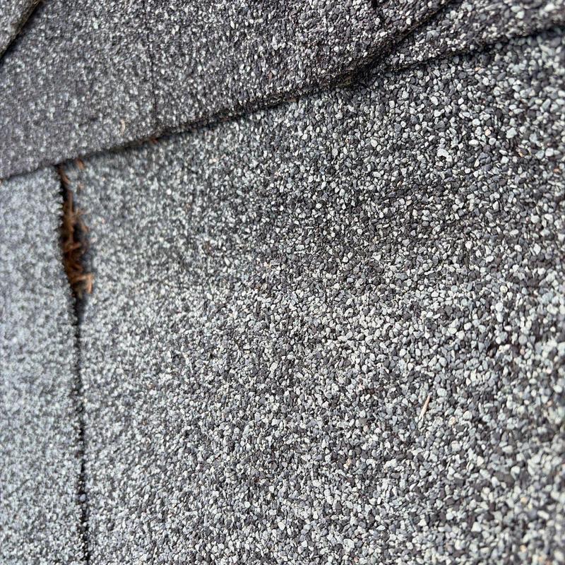 Asphalt shingle roof with damage near seam