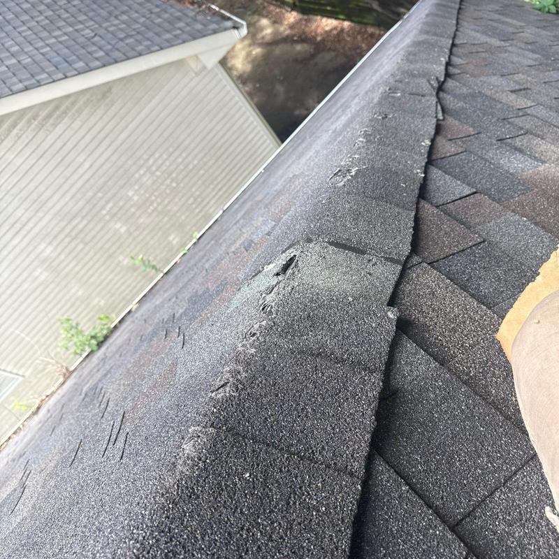 Asphalt shingle ridge with hail damage and wear signs