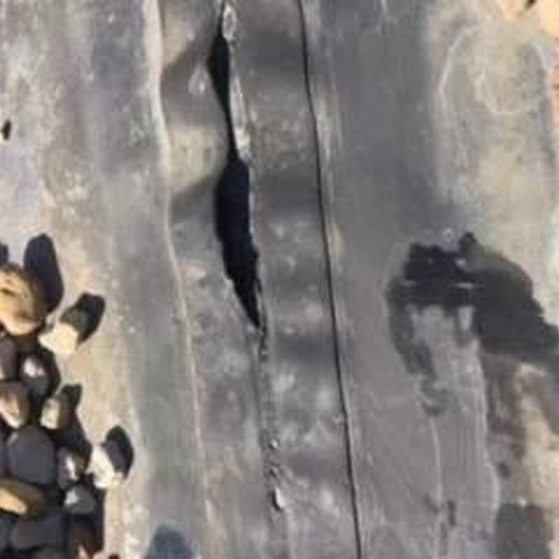 EPDM roofing membrane with split tear and surrounding gravel EPDM roofing membrane with split tear and surrounding gravel