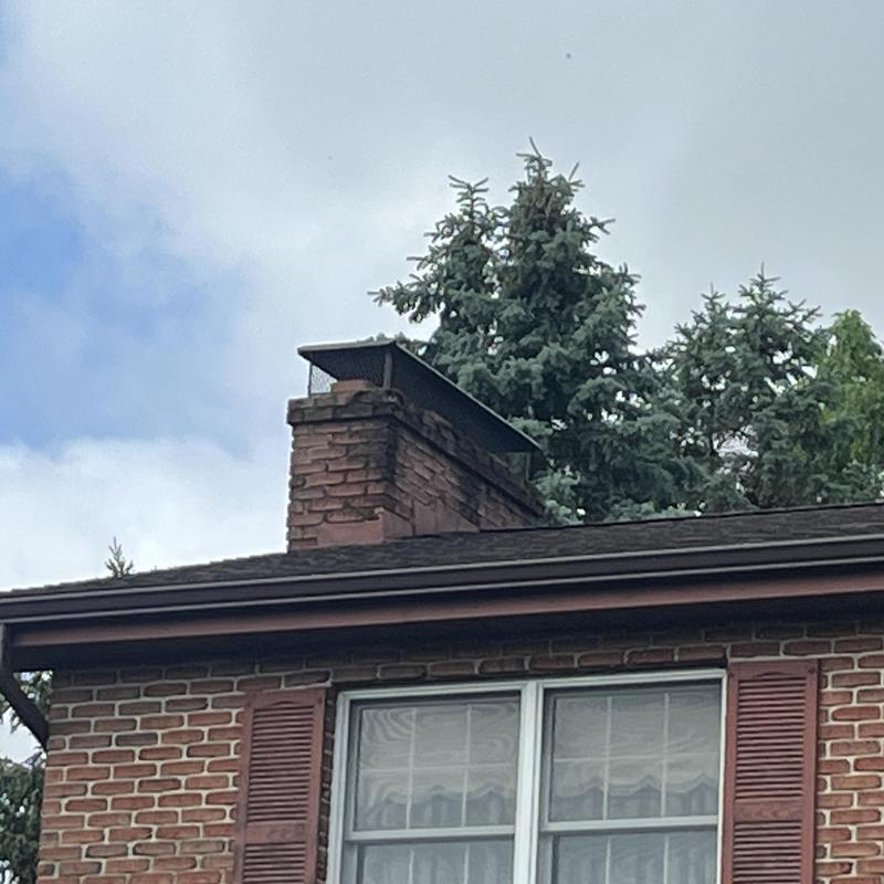Chimney cap and brick chimney on residential roof Chimney cap and brick chimney on residential roof