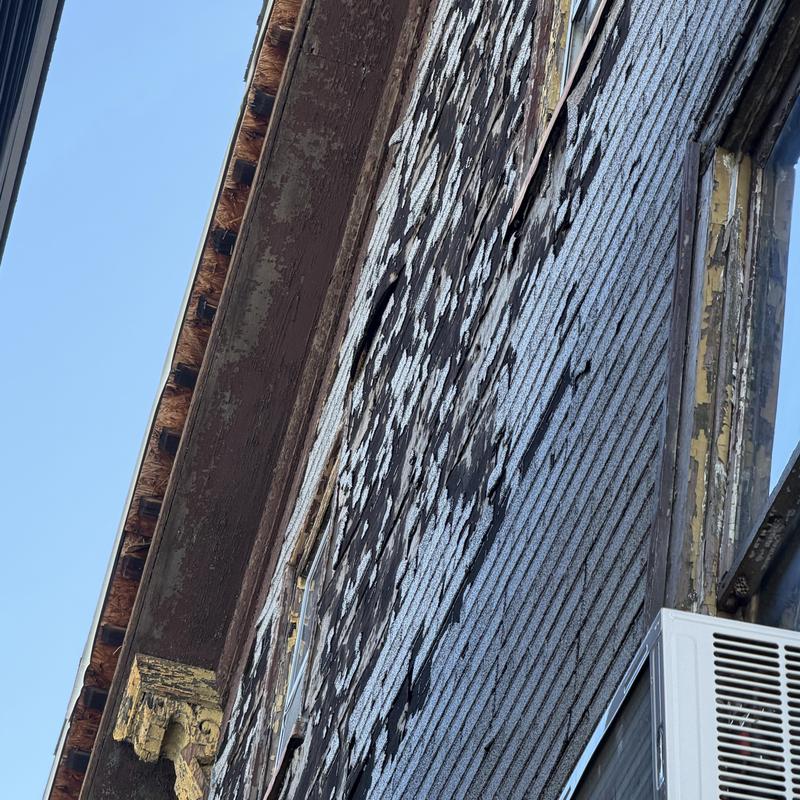 Old wood siding with peeling paint on brick wall Old wood siding with peeling paint on brick wall
