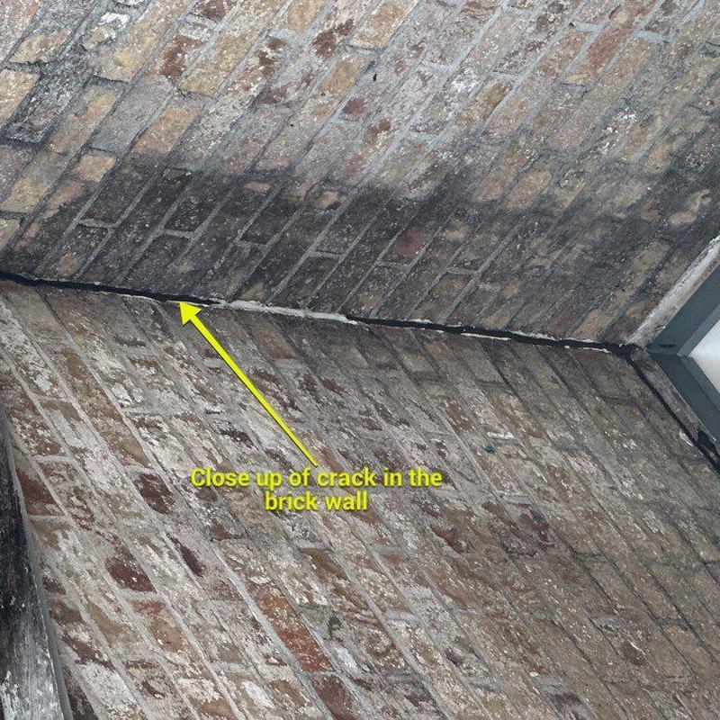 Brick wall with visible crack near ceiling corner Brick wall with visible crack near ceiling corner