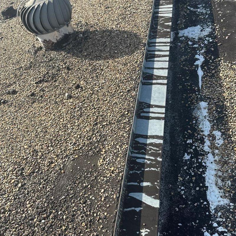 Gravel roof surface with metal flashing and vent turbine Gravel roof surface with metal flashing and vent turbine