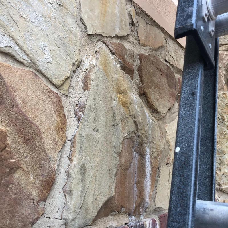Stone veneer wall mortar cracks with ladder nearby Stone veneer wall mortar cracks with ladder nearby