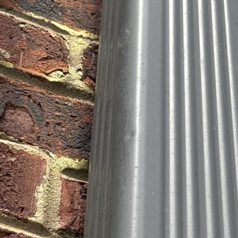 Metal downspout close-up on brick wall exterior