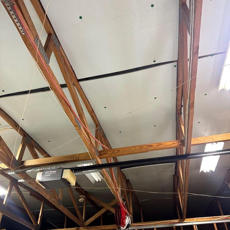 Garage door opener system mounted on wooden rafters