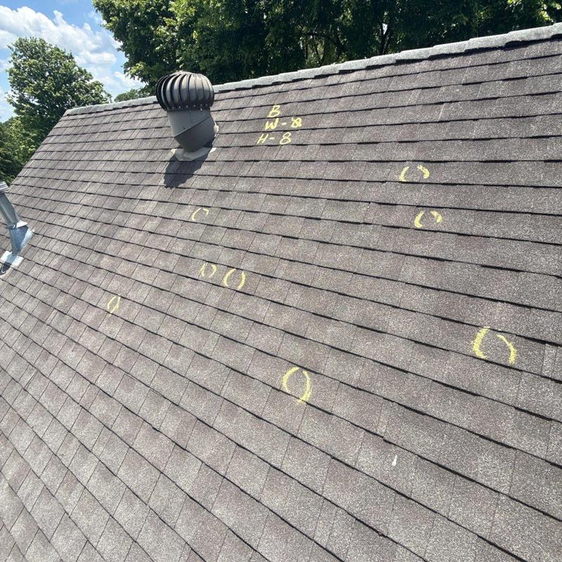 Asphalt shingles with hail damage markings on roof