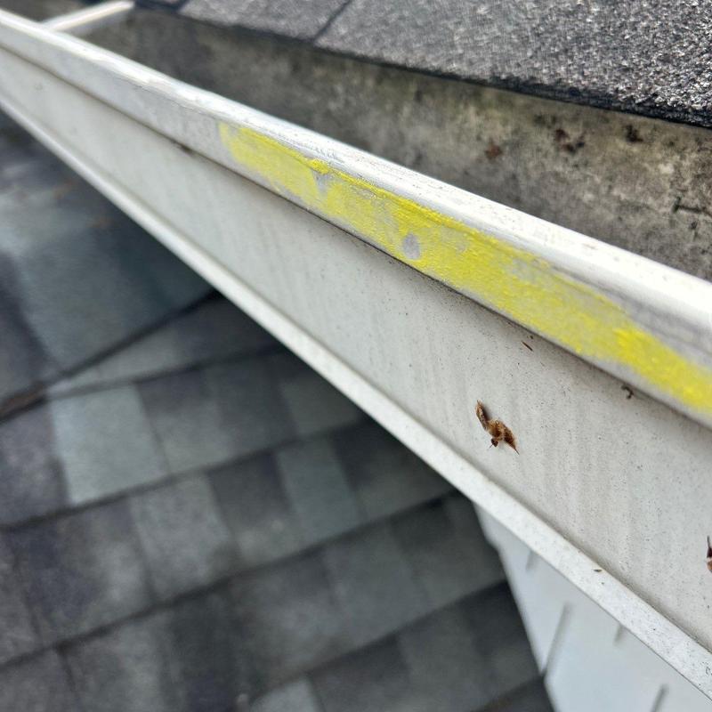 Gutter with yellow hail damage markings on roof edge