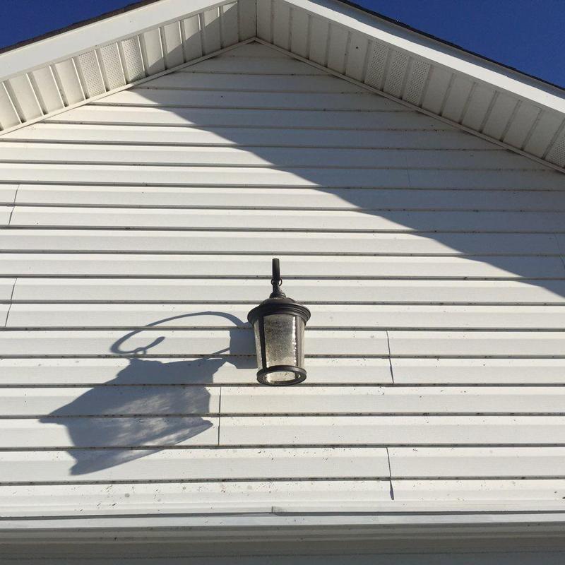 Outdoor wall light fixture on white siding exterior