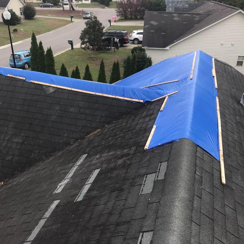 Roof shingles with blue tarp covering ridge and valleys