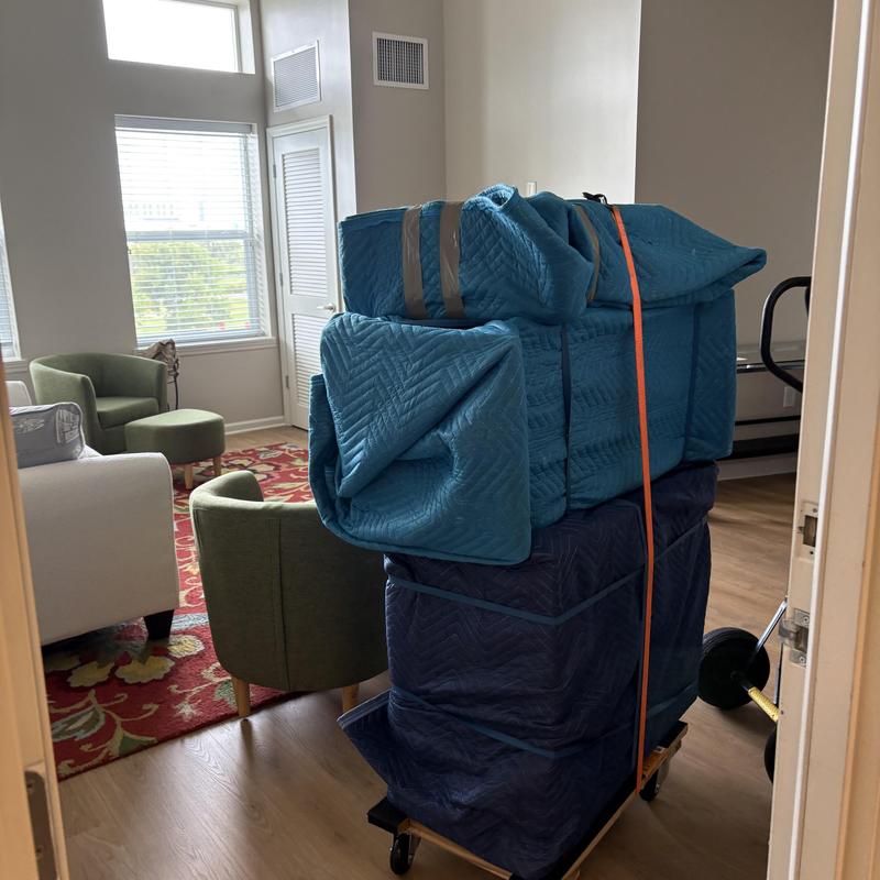 Furniture wrapped in moving blankets on dolly