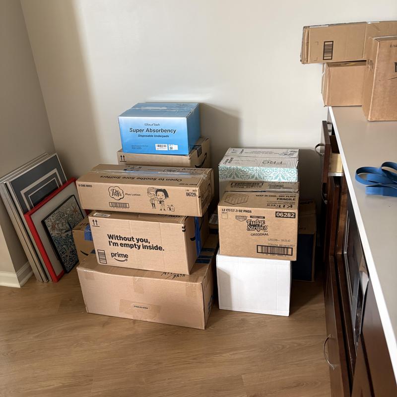 Cardboard moving boxes stacked near wall with framed art