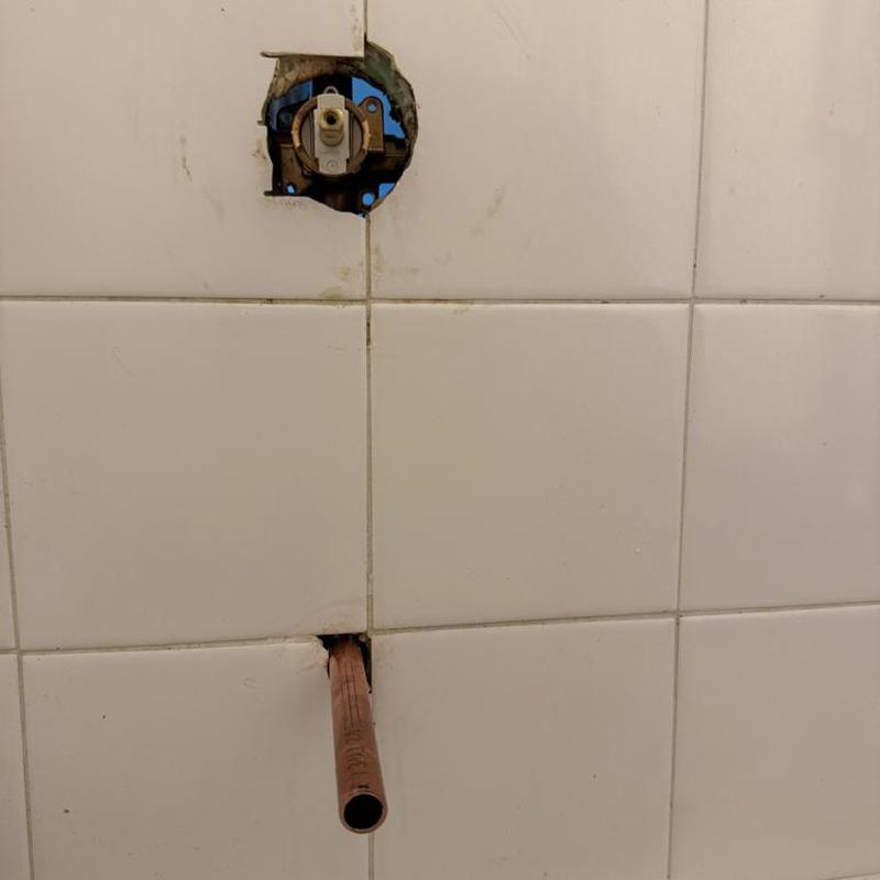 Shower valve plumbing behind tile cutout with copper pipe