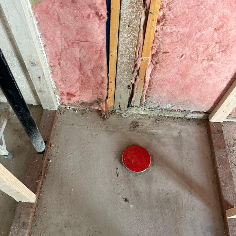 Shower drain pipe installation with red cap and insulation