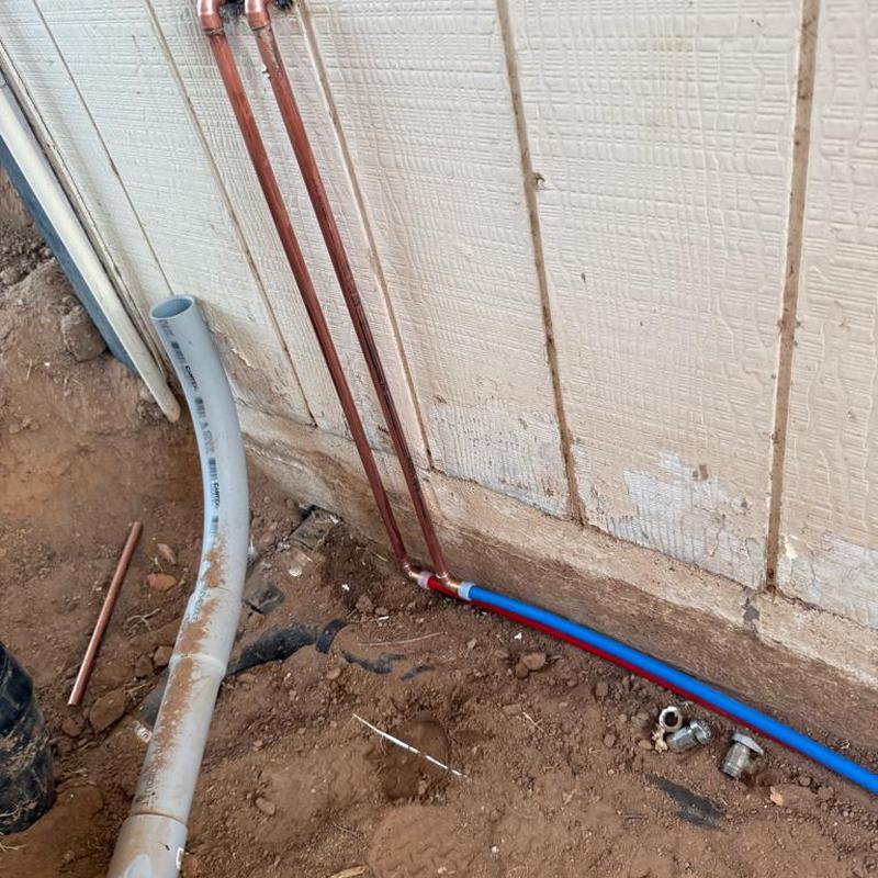 Copper and PEX water lines installed beside foundation wall