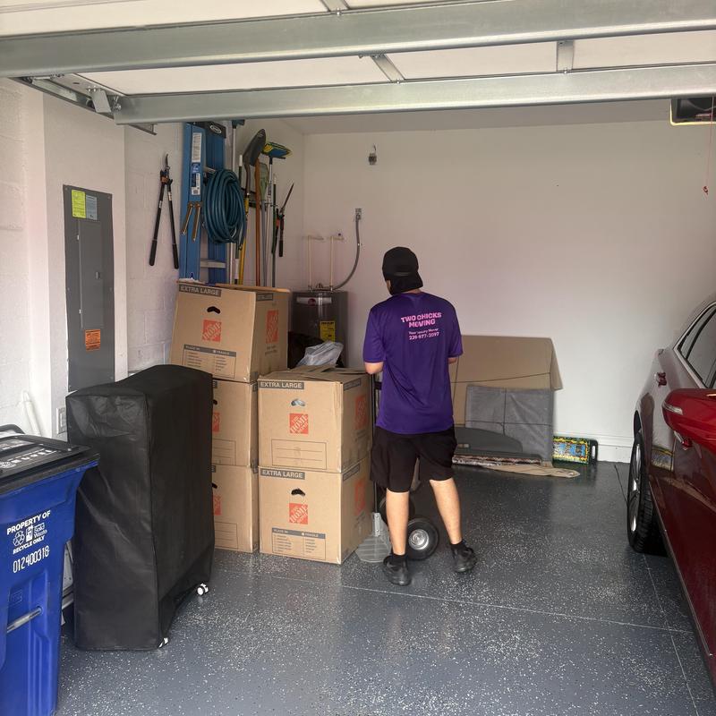 Moving boxes stacked in residential garage with mover