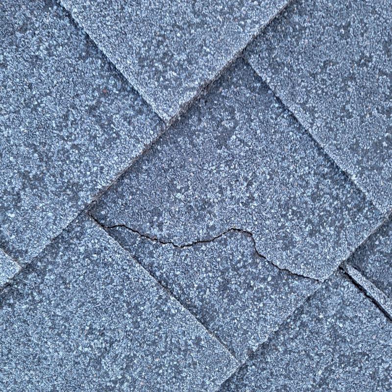 Asphalt roofing shingles with weather-related cracking