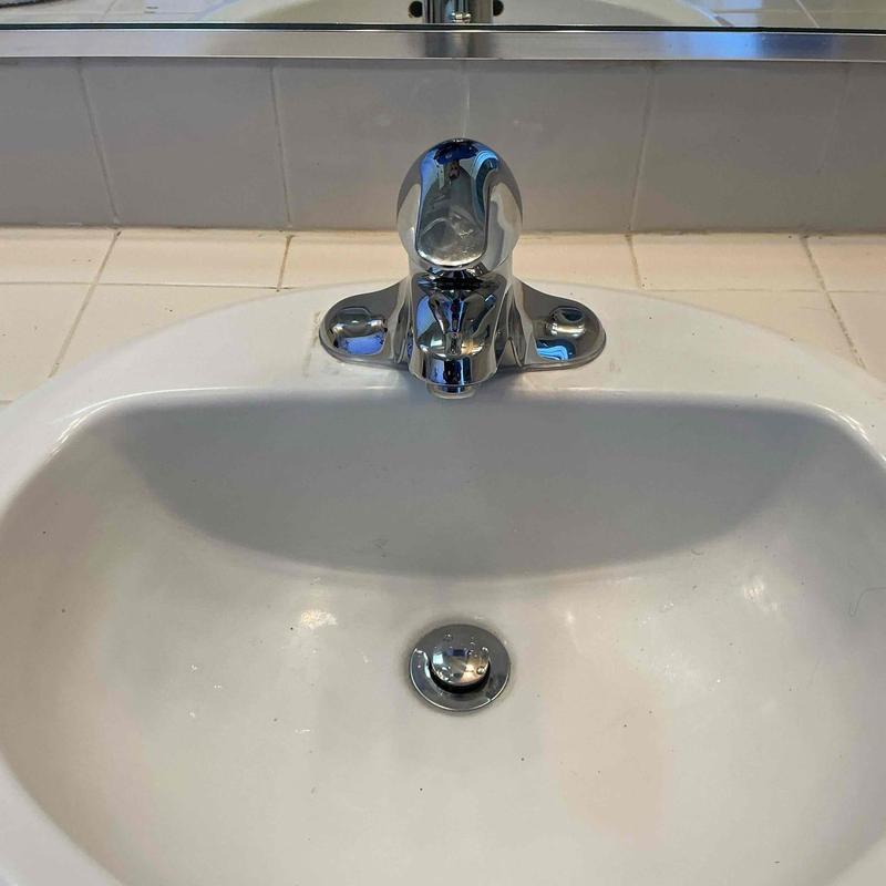 Bathroom sink faucet and basin in white tile bathroom
