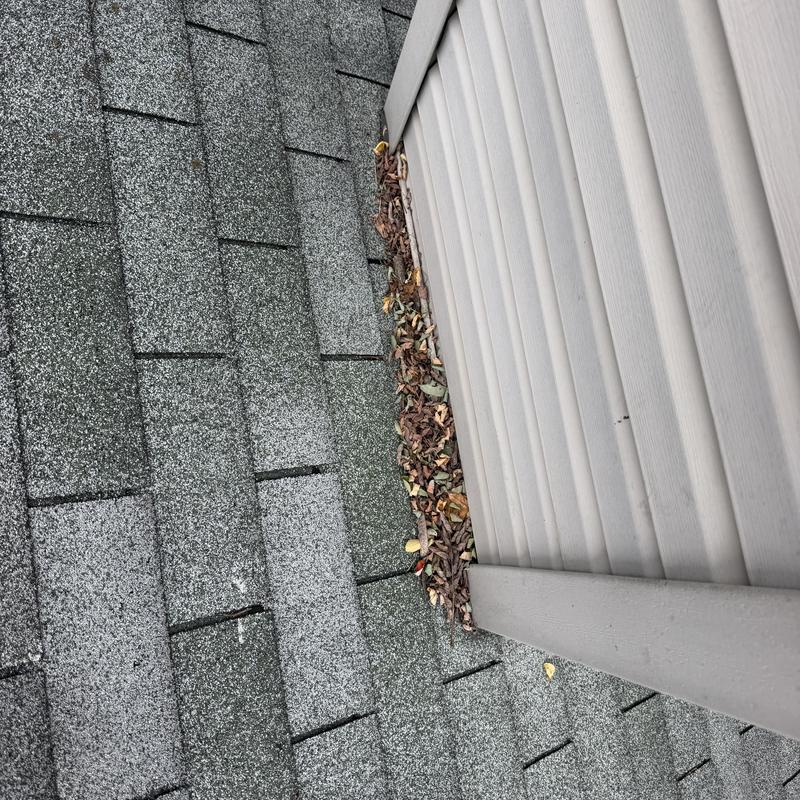 Shingle roof debris buildup near chimney siding Shingle roof debris buildup near chimney siding