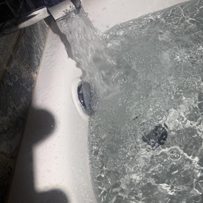 Bathtub overflow drain with running water flowing Bathtub overflow drain with running water flowing