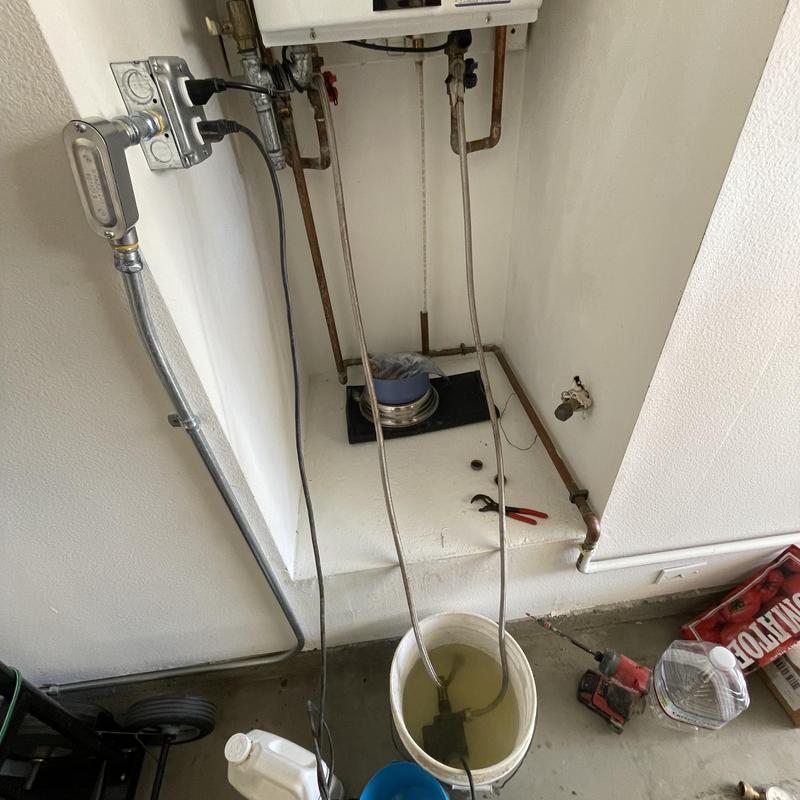Tankless water heater flushing setup with bucket and tools