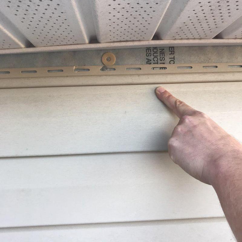 Vinyl siding damage inspection near roof edge panel