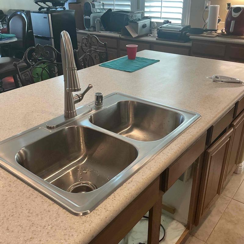 Two-basin kitchen sink with faucet and drain assembly