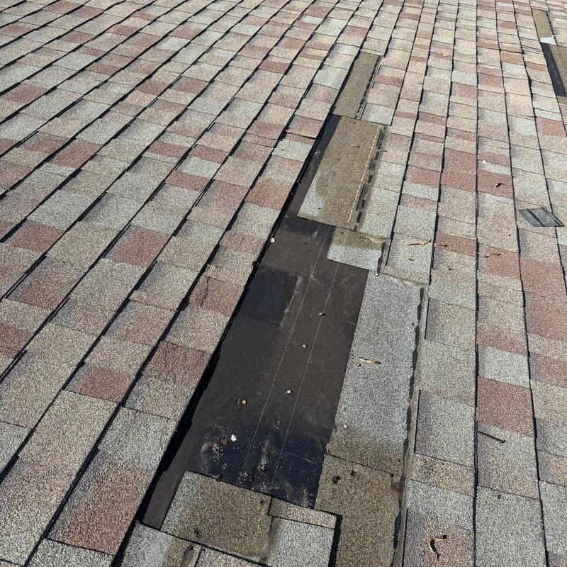 Asphalt shingle roof with damaged shingles and exposed underlayment Asphalt shingle roof with damaged shingles and exposed underlayment