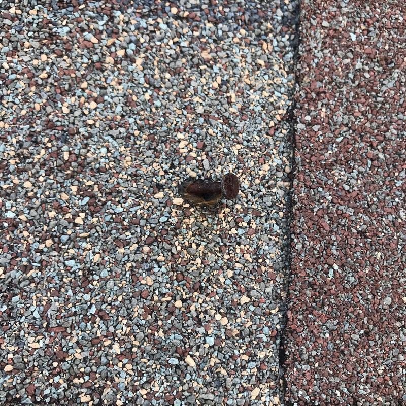 Asphalt roofing shingle with exposed rusted nail close-up Asphalt roofing shingle with exposed rusted nail close-up