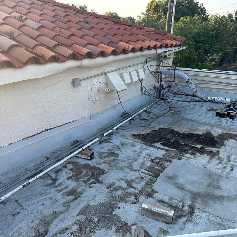 Commercial flat roof surface with damage and wear Commercial flat roof surface with damage and wear
