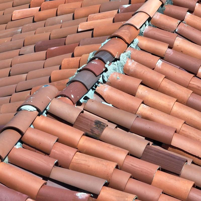 Clay tile roof ridge with visible mortar and repairs Clay tile roof ridge with visible mortar and repairs
