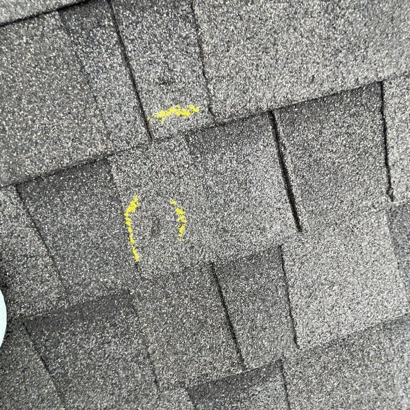 Roof shingles with hail damage marked in yellow paint