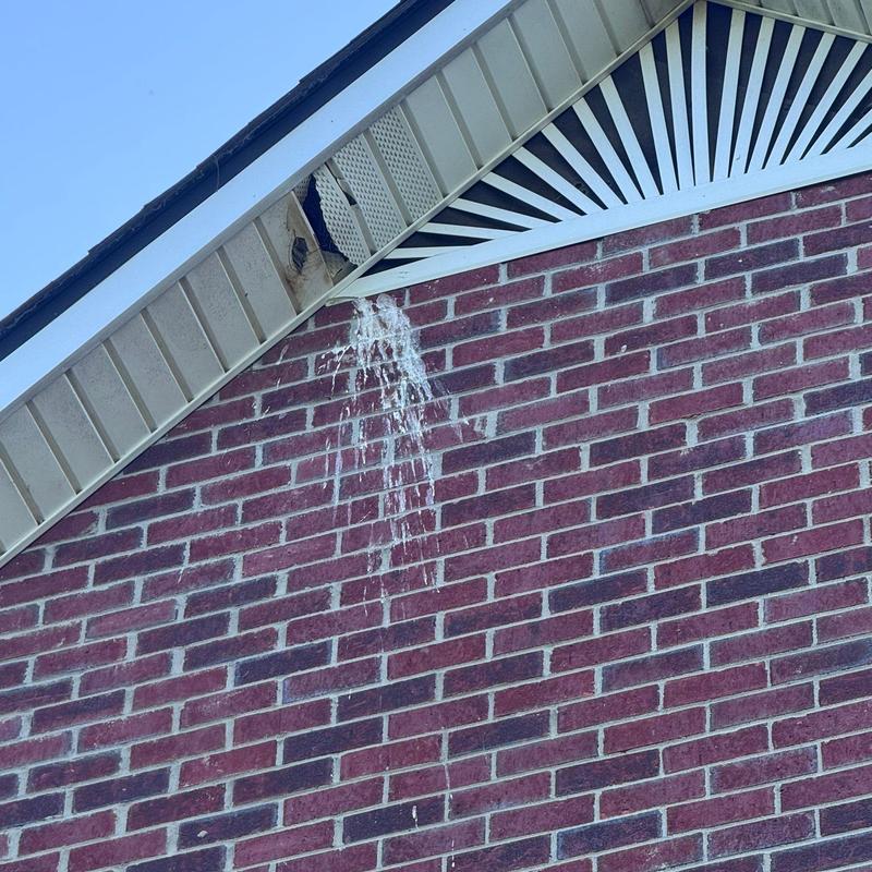 Soffit vent damage with white streaks on brick wall