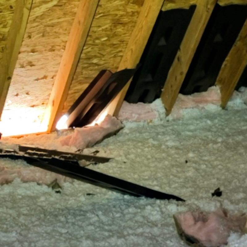 Attic insulation with visible roof vent and wood framing