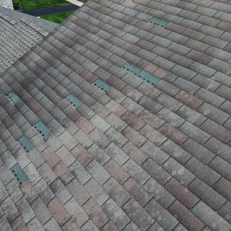 Asphalt shingle roof with wind damage on upper slopes Asphalt shingle roof with wind damage on upper slopes