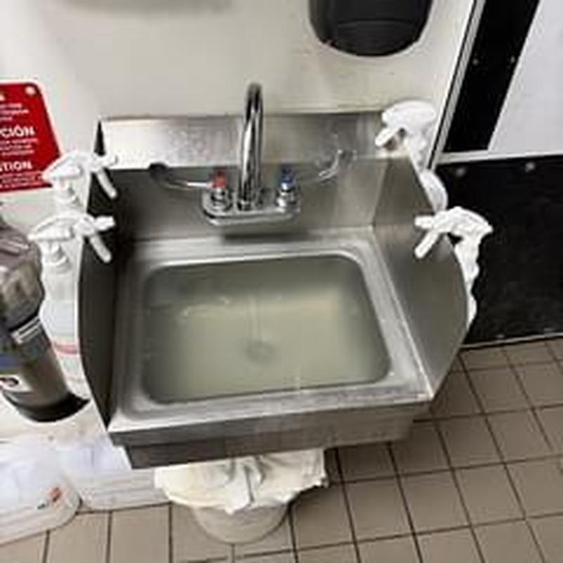Commercial hand sink with clogged drain and standing water