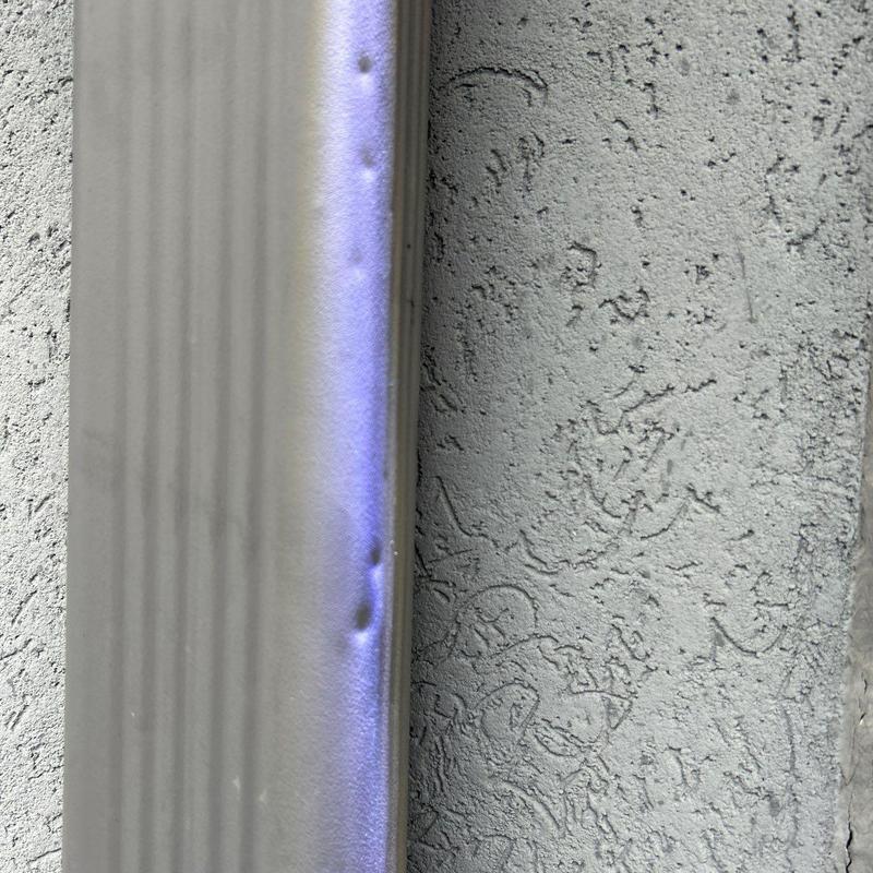Metal downspout with hail damage dents on side panel