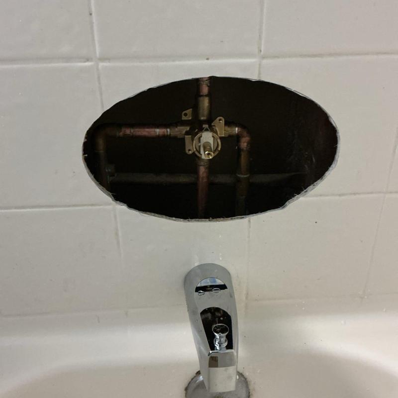 Shower valve and copper pipes behind tile wall cutout