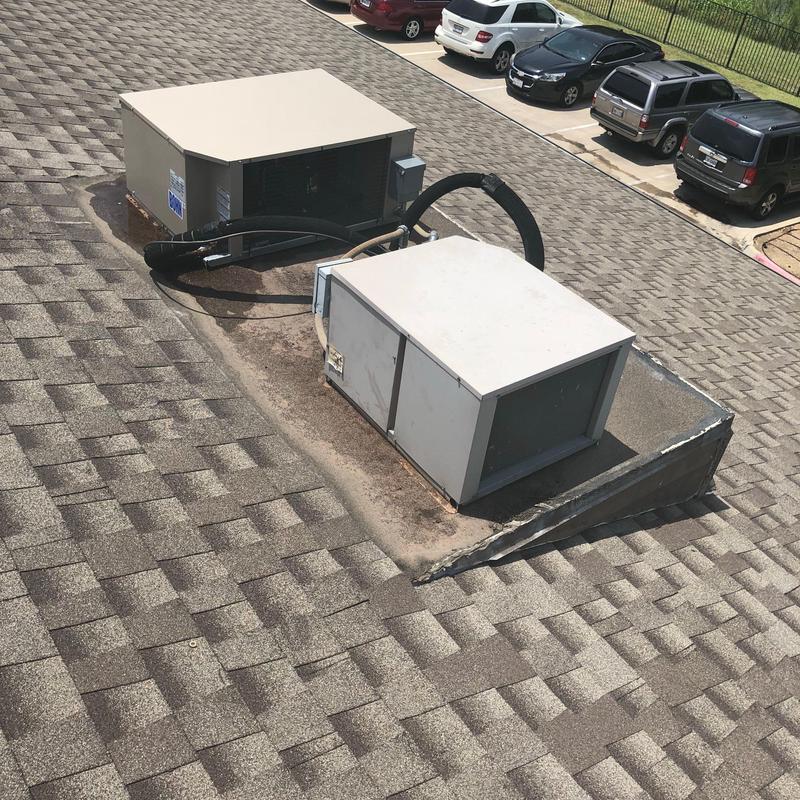 Rooftop HVAC units on asphalt shingle roof with wear signs Rooftop HVAC units on asphalt shingle roof with wear signs