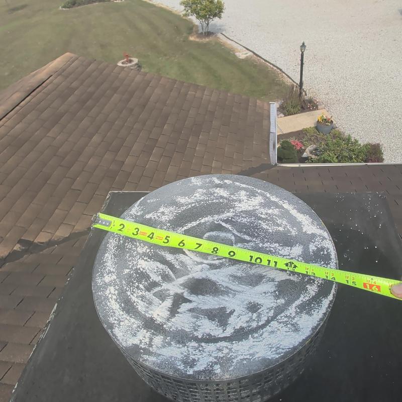 Round metal attic vent with measuring tape on roof