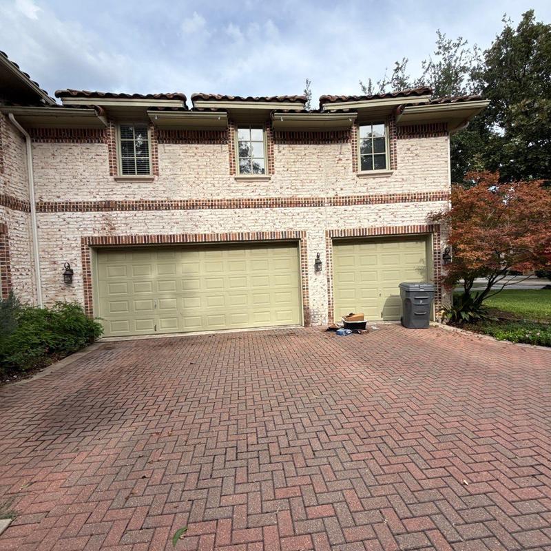 Brick driveway surface with repaired sections near garage doors Brick driveway surface with repaired sections near garage doors