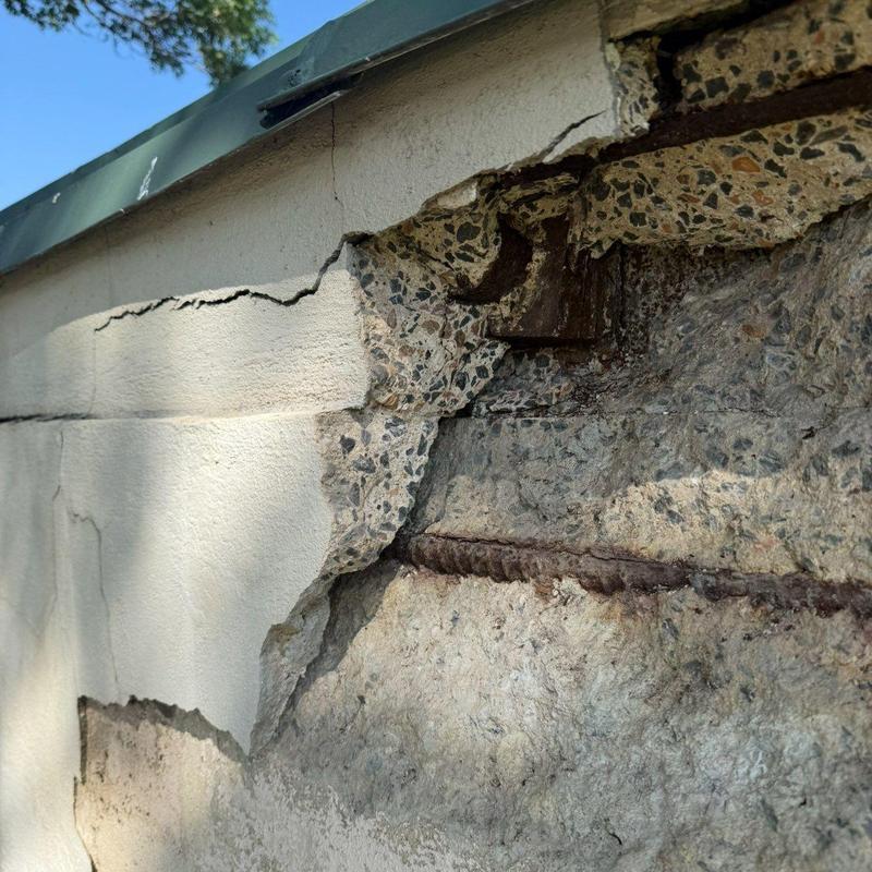 Concrete wall with exposed rebar and surface damage Concrete wall with exposed rebar and surface damage