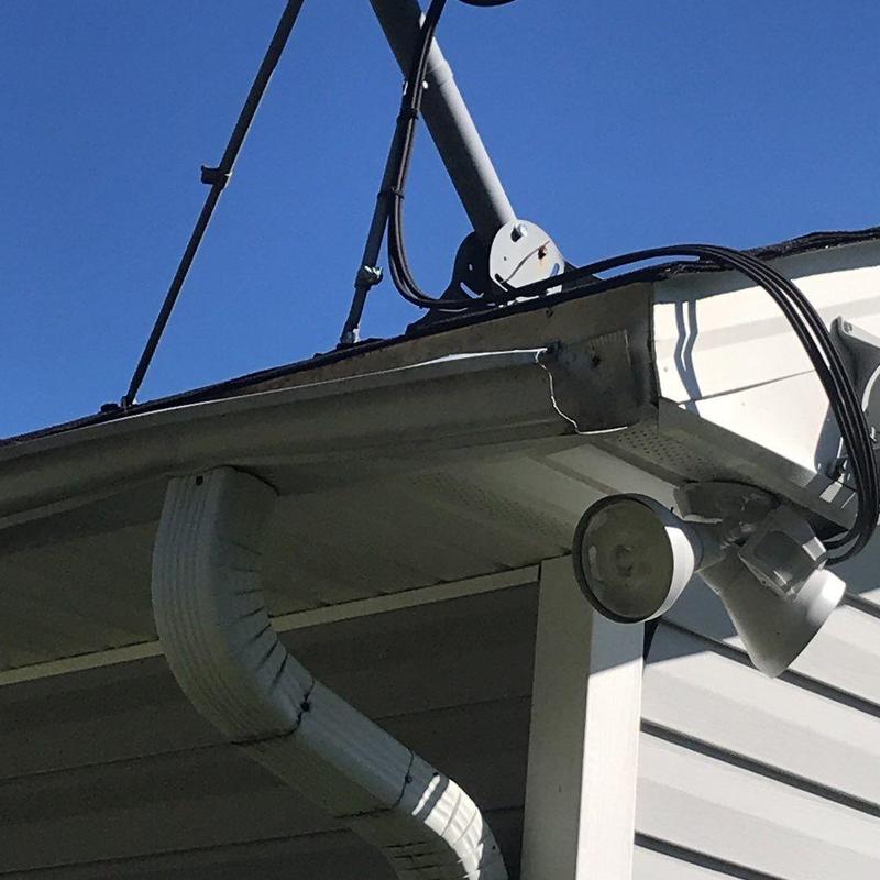 Damaged gutter downspout and roof edge with cables