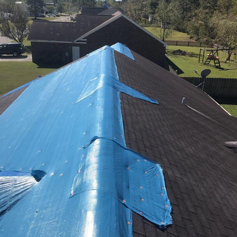 Shingle roof with blue tarp covering damage