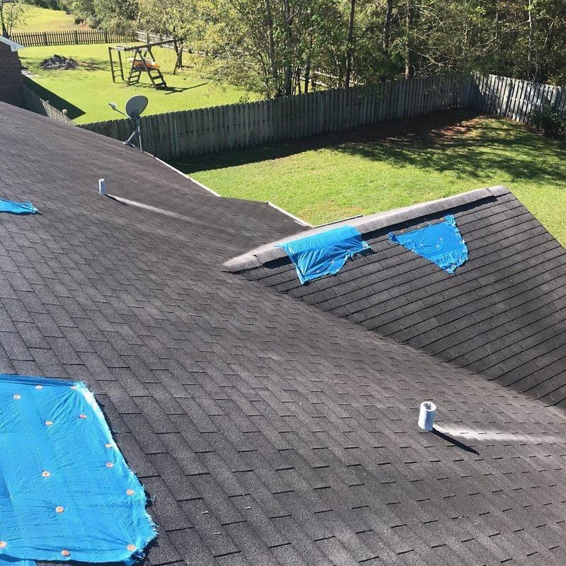 Shingle roof with blue tarp patches on damaged areas