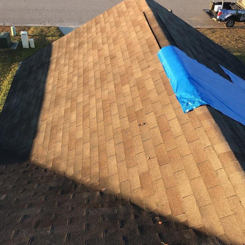 Asphalt shingle roof with blue tarp on ridge cap
