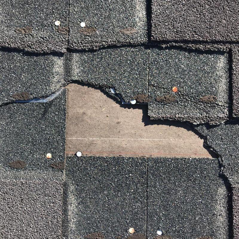 Asphalt shingle roof with missing granules and nails visible